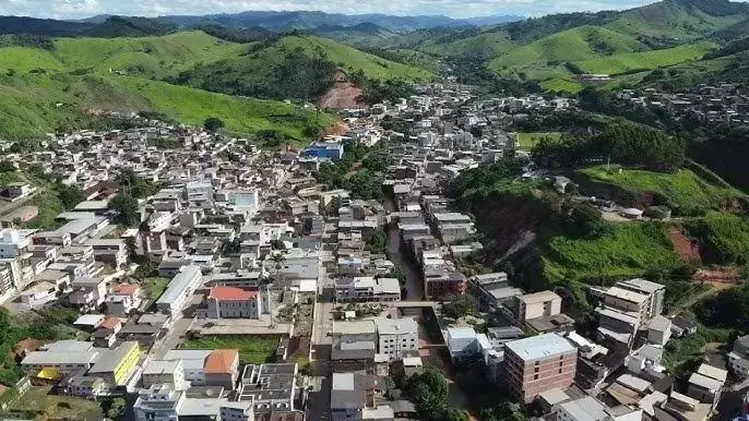 Vista aérea de Inhapim MG, com o centro adensado entre morros verdes e um córrego cortando a cidade
